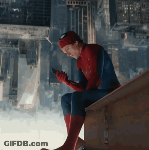A Man In A Spiderman Suit Is Sitting On A Ledge Looking At His Phone GIF