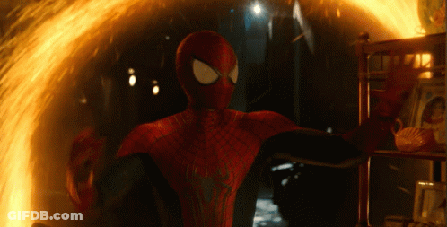 A Man In A Spiderman Suit Is Standing In Front Of A Fire GIF