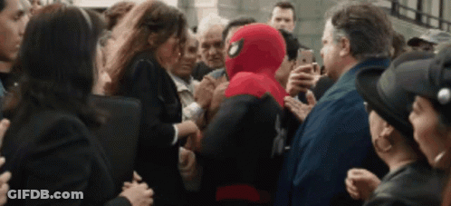 A Man In A Spiderman Suit Is Surrounded By People GIF