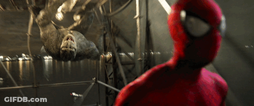 A Man In A Spiderman Suit Looks At A Large Spider GIF