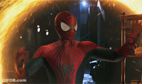 A Man In A Spiderman Suit Stands In Front Of A Fire GIF