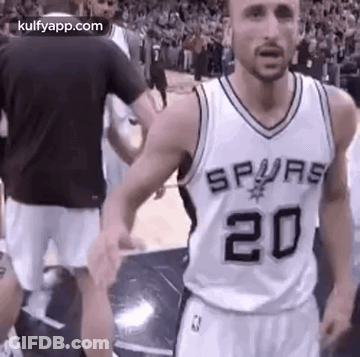 A Man In A Spurs Jersey Is Standing On A Basketball Court With His Hands In The Air . GIF