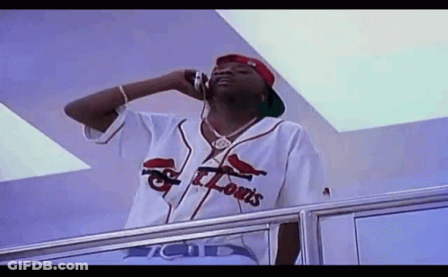 A Man In A St. Louis Baseball Jersey Is Talking On A Cell Phone . GIF