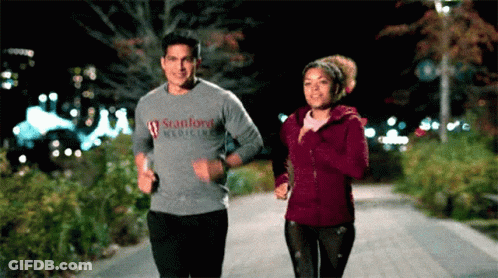 A Man In A Stanford Medicine Shirt Is Jogging Next To A Woman GIF
