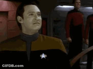 A Man In A Star Trek Uniform Is Making A Funny Face While Standing In Front Of A Group Of People . GIF