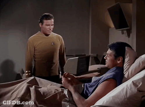 A Man In A Star Trek Uniform Is Standing Next To Another Man In A Hospital Bed GIF