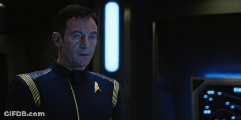 A Man In A Star Trek Uniform Stands Next To A Sign That Says Hold On A Second GIF