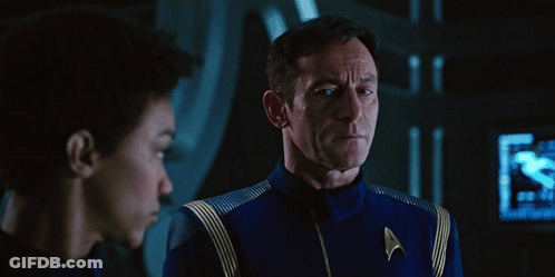 A Man In A Star Trek Uniform Talks To Another Man In A Dark Room GIF