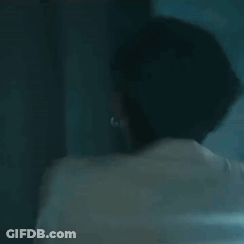 A Man In A Strait Jacket Is Laughing And Smiling In A Dark Room . GIF