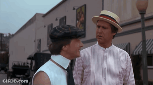 A Man In A Straw Hat Talks To A Woman In A Striped Shirt GIF