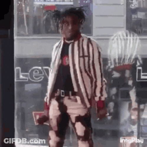 A Man In A Striped Jacket And Pants Is Standing In Front Of A Store . GIF