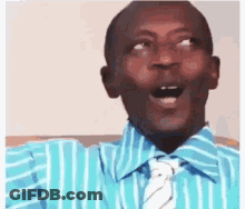 A Man In A Striped Shirt And Tie Is Making A Funny Face . GIF