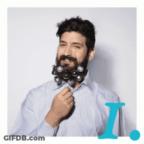 A Man In A Striped Shirt Has A Beard Decorated With Christmas Decorations GIF