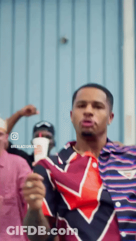 Man In Striped Shirt Dancing In Front Of Blue Wall GIF