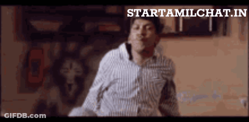 A Man In A Striped Shirt Is Dancing In Front Of A Sign That Says Startamilchat.in GIF