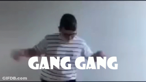 A Man In A Striped Shirt Is Dancing In Front Of A Wall With Gang Gang Written On It GIF