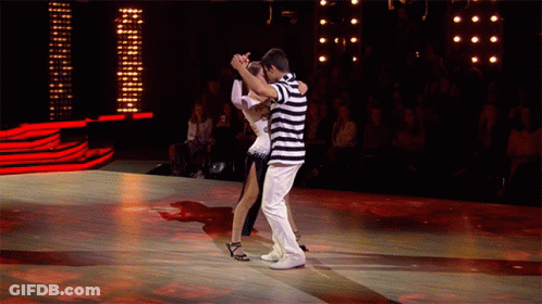 A Man In A Striped Shirt Is Dancing With A Woman In A White Dress On A Dance Floor GIF