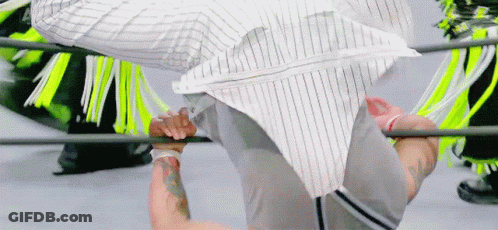 A Man In A Striped Shirt Is Doing A Handstand In A Boxing Ring . GIF