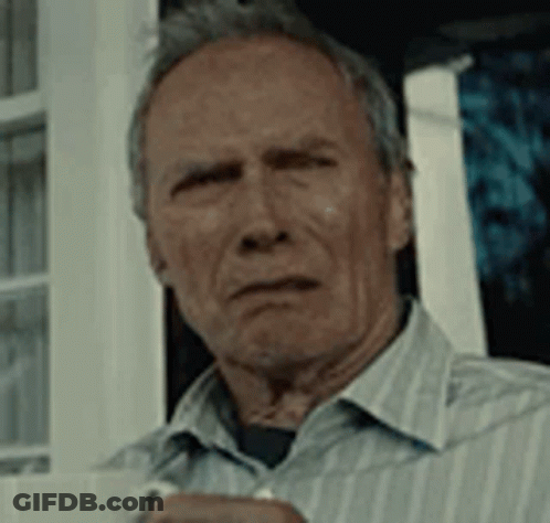 A Man In A Striped Shirt Is Holding A Cup Of Coffee And Looking At The Camera . GIF