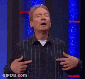 A Man In A Striped Shirt Is Holding His Hands To His Chest And Pointing At His Chest . GIF