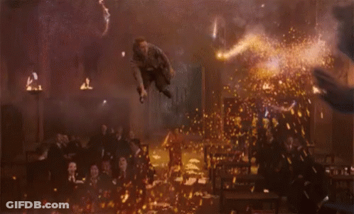 A Man In A Striped Shirt Is Jumping In The Air In Front Of A Crowd GIF