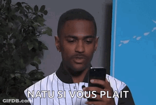 A Man In A Striped Shirt Is Looking At His Cell Phone And Says Natu Si Vous Plait GIF