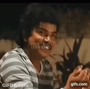 A Man In A Striped Shirt Is Making A Funny Face While Holding A Cell Phone . GIF