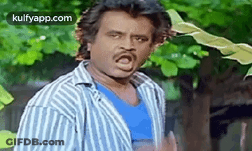A Man In A Striped Shirt Is Making A Funny Face While Standing In Front Of A Tree . GIF