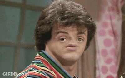 A Man In A Striped Shirt Is Making A Funny Face With His Mouth Open . GIF