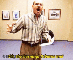 A Man In A Striped Shirt Is Saying Oh The Burning It Burns Me While Holding A Piece Of Paper GIF