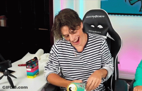 A Man In A Striped Shirt Is Sitting In A Dxracer Chair Laughing GIF