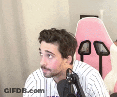 A Man In A Striped Shirt Is Sitting In Front Of A Microphone . GIF