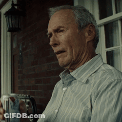 A Man In A Striped Shirt Is Sitting On A Porch Holding A Cup GIF