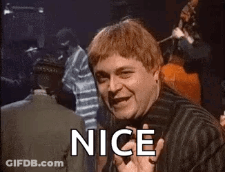 A Man In A Striped Shirt Is Smiling And Waving At The Camera With The Word Nice . GIF