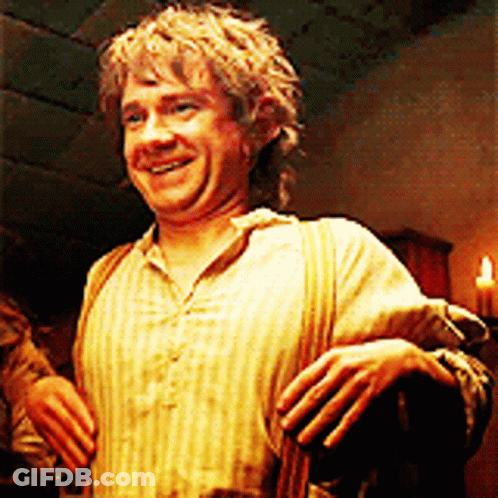 A Man In A Striped Shirt Is Smiling In A Dark Room With A Candle In The Background . GIF