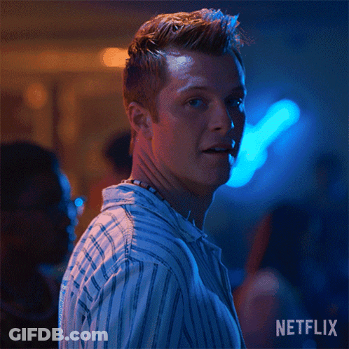 A Man In A Striped Shirt Is Smiling In A Dark Room With Blue Lights . GIF