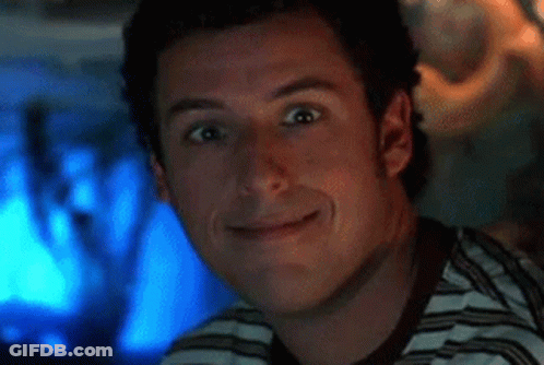 A Man In A Striped Shirt Is Smiling In Front Of A Computer Screen . GIF