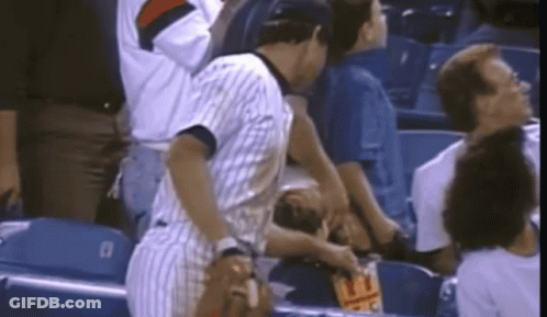 A Man In A Striped Shirt Is Standing In A Stadium Holding A Bag Of Chips GIF