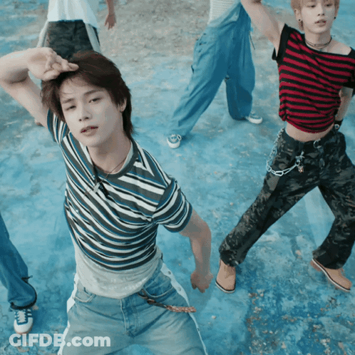 A Man In A Striped Shirt Is Standing In Front Of A Group Of People GIF