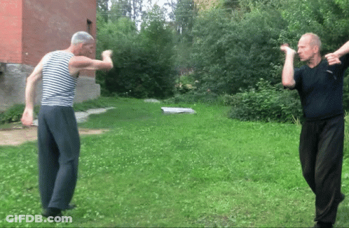 A Man In A Striped Shirt Is Standing In The Grass GIF