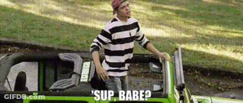 A Man In A Striped Shirt Is Standing Next To A Green Car With The Words Sup Babe Written On It . GIF
