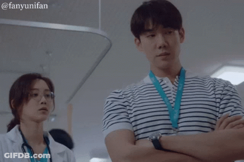 A Man In A Striped Shirt Is Standing Next To A Woman In A White Lab Coat GIF