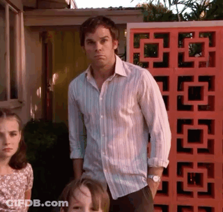 A Man In A Striped Shirt Is Standing Next To Two Children In Front Of An Orange Wall GIF