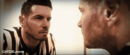 A Man In A Striped Shirt Looks At His Reflection In The Mirror GIF
