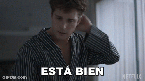 A Man In A Striped Shirt Says Esta Bien In White Letters GIF