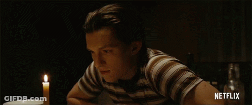 A Man In A Striped Shirt Sits At A Table With A Candle And Says Netflix On The Bottom Right GIF