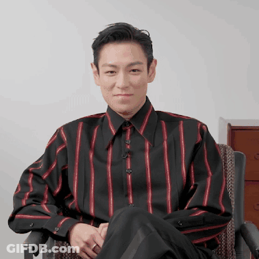 A Man In A Striped Shirt Sits In A Chair GIF