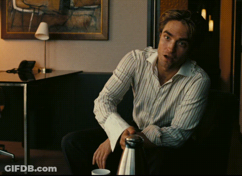 A Man In A Striped Shirt Sits In Front Of A Table GIF