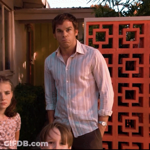 A Man In A Striped Shirt Stands In Front Of An Orange Block GIF
