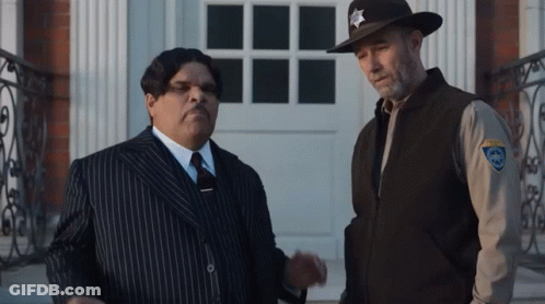 A Man In A Striped Suit Stands Next To A Sheriff In A Cowboy Hat GIF